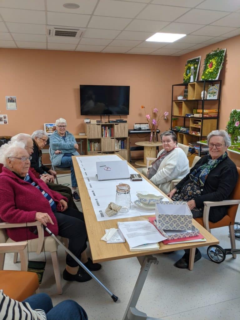 Atelier mémoires et souvenirs dans une résidence services. Les résidents sont autour d'une table et participent à la frise chronologique.