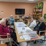 Atelier mémoires et souvenirs dans une résidence services. Les résidents sont autour d'une table et participent à la frise chronologique.