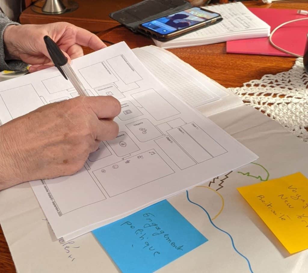 Des documents sont disposés sur une table. Une main tient un stylo et rempli le schéma pour raviver les souvenirs.